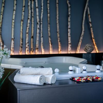 Whirlpool mit zwei Gläsern Champagner und Früchten am Beckenrand 