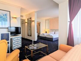 Orange karierte Couch neben einem passenden Sessel gegenüber eines Tisches mit Kaffeestation