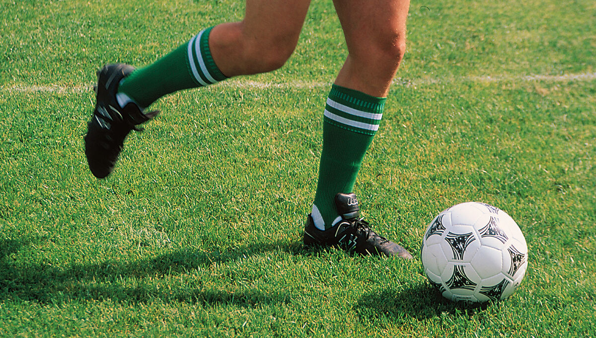 Person kickt einen Fußball