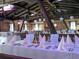 Lange weiß gedeckte Tafel in der traditionellen Almhütte 