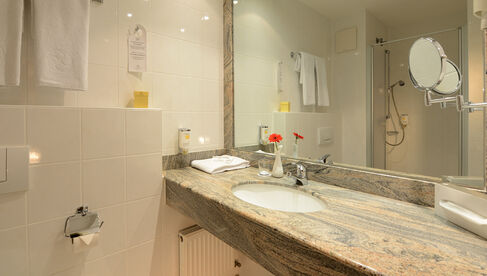 Helles Badezimmer mit Dusche und großem Spiegel 